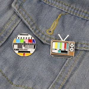 Retro TV signal enamel pin set with colorful test bars on blue denim fabric
