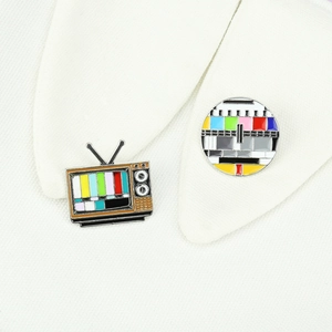 Detail of retro TV and test card enamel pins with vibrant colors on white fabric