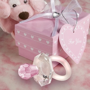 Detailed macro view of a pink crystal pacifier souvenir with a soft pink gift box background