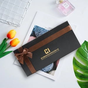 Close-up of premium black gift box with a textured leather finish and brown satin ribbon bow