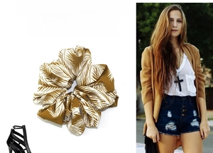 Detail of yellow mustard scrunchie with white palm leaf print on textured fabric
