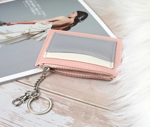 Detail of multi-color paneled women's wallet with metal keychain and zipper on wood surface