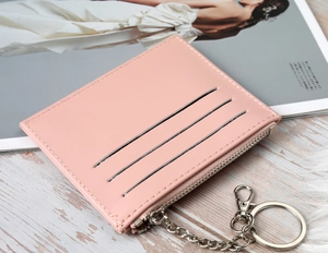Pink PU leather card holder with 3 slots and keychain chain on a wooden desk