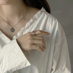 Detailed view of sterling silver coin pendant necklace and star ring worn on model