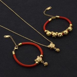 Detail of titanium steel rat charm necklace and red braided zodiac bracelets on black fabric