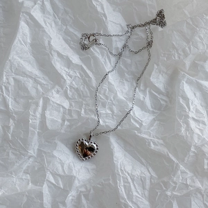 Detailed view of S925 sterling silver heart pendant necklace on textured paper