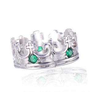 Detailed macro view of silver crown ring with green gemstones and cross pattern