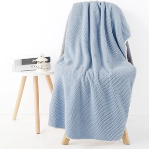 Blue waffle weave blanket with beige trim draped over a modern grey fabric chair