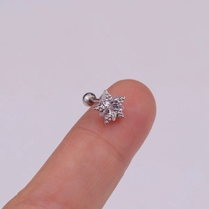 Macro detail of a small silver star cartilage stud earring with cubic zirconia on a fingertip