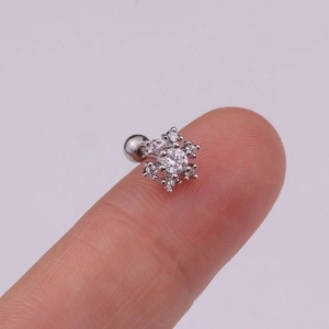 Macro view of a snowflake helix piercing stud with zircon on a person fingertip
