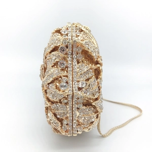 Detail of gold evening clutch bag featuring intricate hollow leaf design and white rhinestones