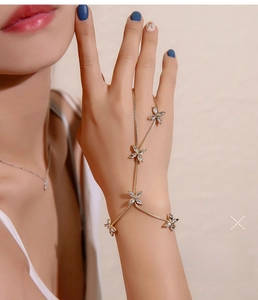 Gros plan d'un bracelet bague doré avec des breloques fleurs en zircon sur une main de femme