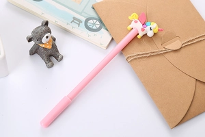 Pink unicorn gel pen with a 3D unicorn topper on a white desk with aesthetic props