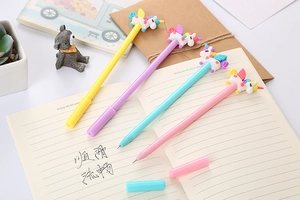 Detailed view of four colorful unicorn gel pens with soft silicone toppers on a notebook
