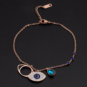 Detailed view of rose gold layered bracelet with blue evil eye and teardrop crystal charms