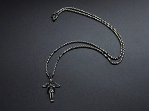 Macro shot of antique silver angel pendant and stainless steel chain on black matte texture