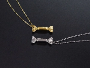 Detailed view of candy-shaped gold and silver pendants on matching metal necklaces