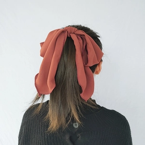 Elegant red bow hair tie with long ribbons on a high ponytail, minimalist Korean style