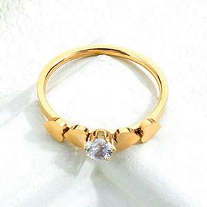 Golden heart ring with central zircon stone on white textured stone background