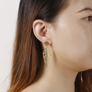 Elegant gold hollow leaf earrings with silver bar on model in a stylish profile view