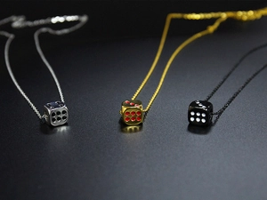 Three lucky dice pendants in silver, gold and black titanium steel on a dark background