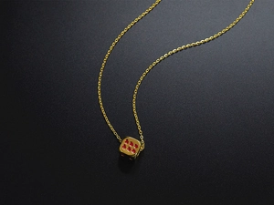 Macro shot of a gold lucky dice pendant with red dots on a sleek titanium steel chain