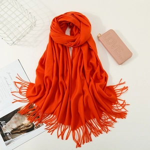 Detail shot of soft orange cashmere-like scarf with fringe texture and thick weave