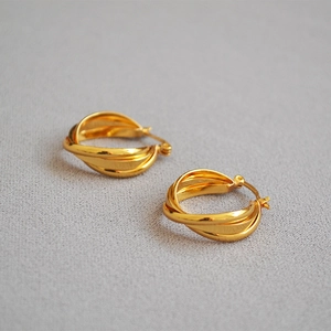 Detailaufnahme von 18K vergoldeten Creolen aus Messing mit eleganter gedrehter Textur