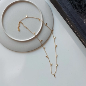 Detailed close-up of a minimalist gold sterling silver necklace with tiny leaf pendants