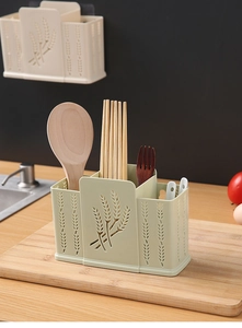 Close-up of a green wall-mounted utensil holder with hollowed wheat pattern and compartments