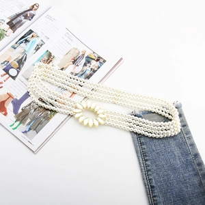 Detail of four-layer pearl belt with sunflower rhinestone buckle on denim pants