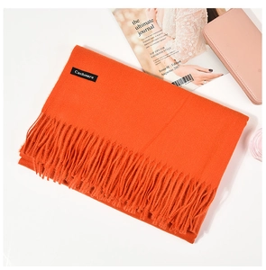 Close-up of orange cashmere scarf showing fine knit texture and long tassel details