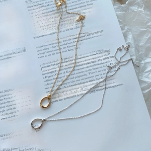Close-up of minimalist gold and silver twisted hoop necklaces on a white book page