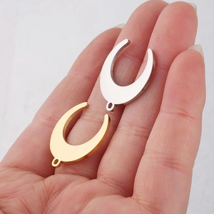 Gold and silver crescent moon stainless steel pendants shown on hand for size reference