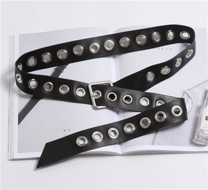 Detail of black wide leather belt with double row silver metal eyelets on a magazine