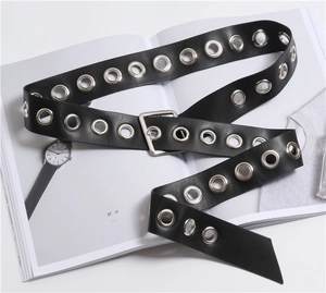Detail of black PU leather belt with silver grommets and square buckle on a magazine