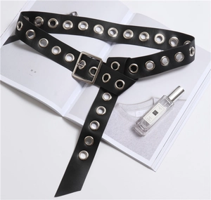Close-up of a black PU leather belt with silver eyelets and square buckle on a magazine