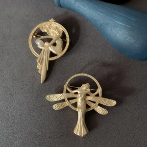 Detailed macro view of matte gold angel brooches with pearls in vintage baroque style