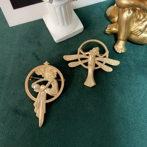 Detailed view of matte gold Art Nouveau brooches with pearls on green velvet