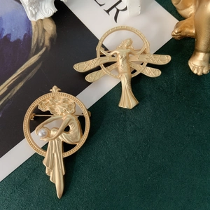 Close-up of matte gold baroque brooch with relief figure and white pearl detail
