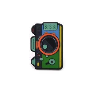Detailed close-up of a colorful enamel camera pin badge for camping enthusiasts
