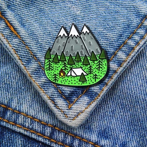 Outdoor camping enamel pin featuring mountains and forest on blue denim jacket