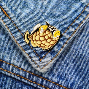Detailed view of sea fish enamel pin featuring yellow patterns on blue denim fabric