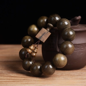 Macro detail of 20mm ebony wood beads with square plaque and gourd charms on a teapot