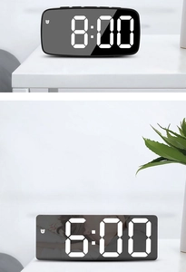 Macro detail of modern black LED mirror alarm clock with white digits on a white desk