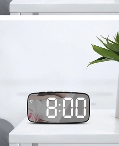 Detailed view of digital mirror alarm clock with white LED time display on white desk