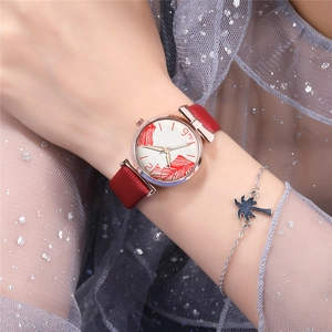 Detail of red leather watch strap with rose gold case and feather dial next to a bracelet