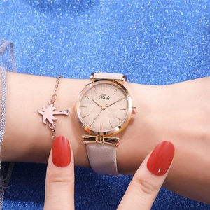 Close-up of women's rose gold quartz watch with leaf pattern dial and palm tree bracelet