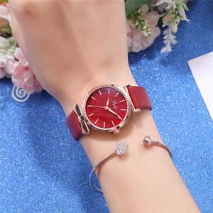 Close-up of red dial quartz watch with leaf pattern and heart bracelet on wrist