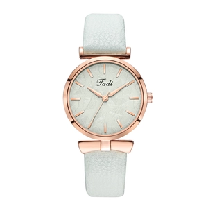 Detail of rose gold quartz watch featuring a white leaf pattern dial and leather strap